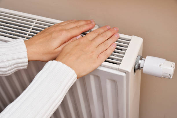 istock A woman warms her hands by the radiator 2192123050