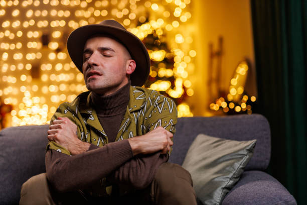 istock Man relaxing on a couch with warm lights in the background indoors 2192125108