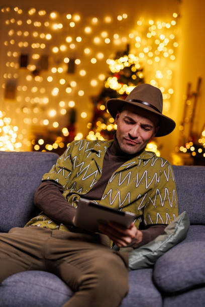 istock Man relaxing on sofa with tablet during festive holiday season in cozy setting 2192125152