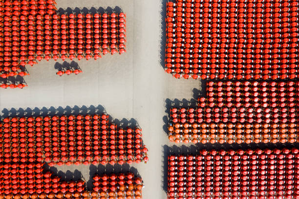 Large group of a red small-scale concrete/mortar mixers. This portable concrete/mortar mixers have wheels and a towing tongue so that it can be towed by a motor vehicle and moved around the worksite by hand, and its rotation is powered by mains electricity. The lever allows the concrete/mortar to be tipped into a wheelbarrow.