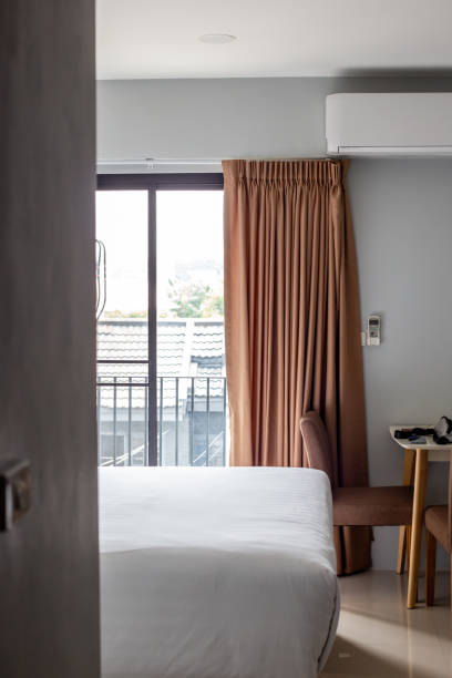 istock Bedroom interior. Large bed and table, lighting from the window with a balcony, air conditioning on the wall 2192126759