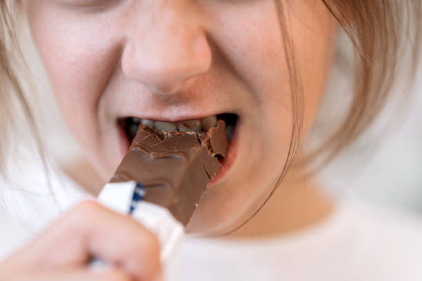istock girl with long hair biting chocolate bar 2192129740