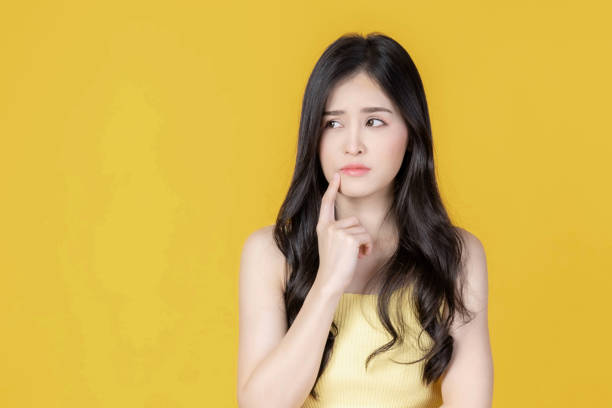 istock Beautiful Asian Woman Thinking with a Curious and Thoughtful Expression, Isolated on Yellow Background, Representing the Concept of Decision Making, Problem Solving, Ideas, and Creative Contemplation 2192132194
