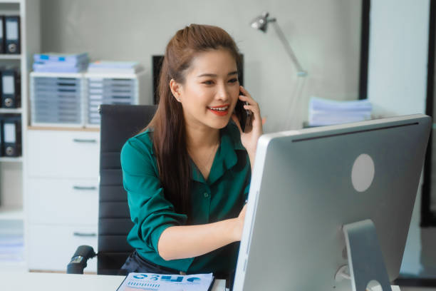 Attractive Asian businesswoman in formal business attire is working at her desk with a laptop and mobile phone, focusing on corporate law, contracts, compliance, and law firm marketing strategies. una atractiva empresaria asiática con atuendo formal de negocios trabaja en su escritorio con una computadora portátil y un teléfono móvil, centrándose en el derecho corporativo, los contratos, el cumplimiento y las estrategias de marketing de los buf