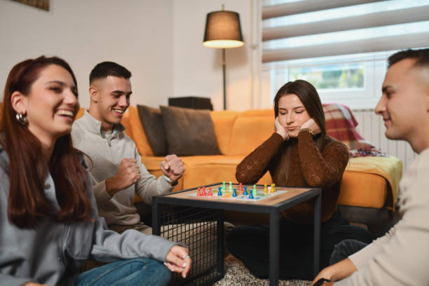 istock Joyful Male Cheering After Winning in Board Game While Defeated Female Is Sitting With Sad Expression 2192134030