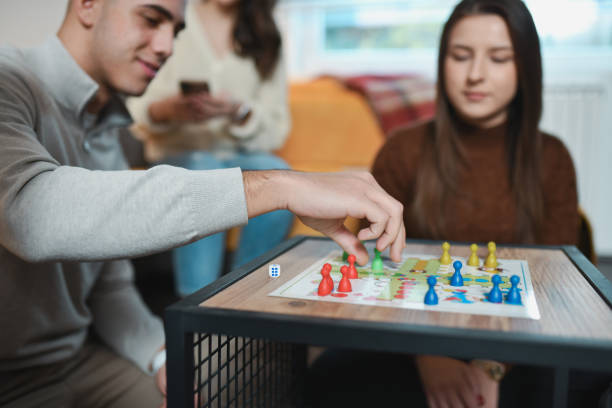 istock Male Player Relocating Figures While Playing Ludo Game With Friends 2192134186