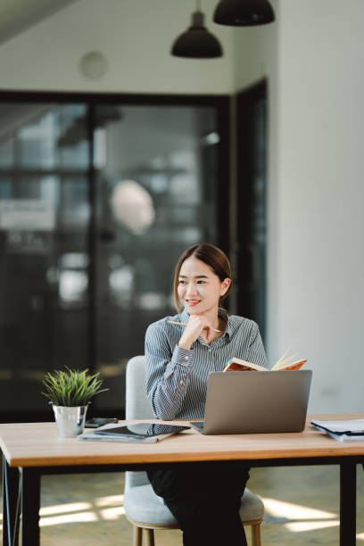 istock Beautiful Asian female student studying online and taking notes Female accountant makes annual financial and tax reports. 2192134473