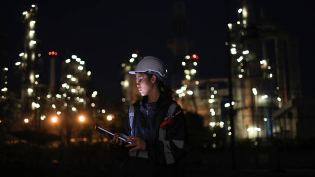 istock Engineer woman using digital tablet working late at night with refinery plant on background. 2192140428