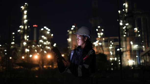 istock Engineer woman using digital tablet working late at night with refinery plant on background. 2192140437