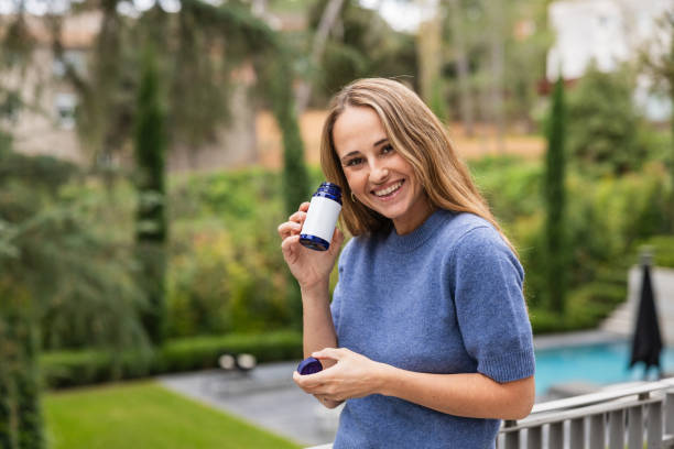 istock Smiling woman holding a pill bottle on a terrace 2192142887