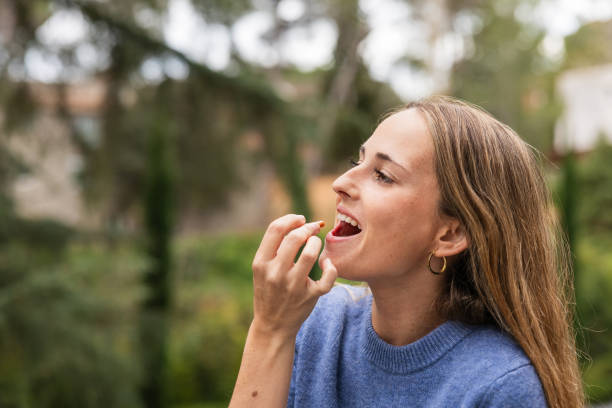 istock Young woman taking vitamin pill outdoors 2192142909