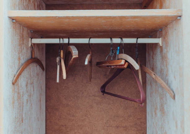 Wooden hangers hang in an empty wardrobe with some signs of wear and rustic charm showcasing their utility and design stock photo