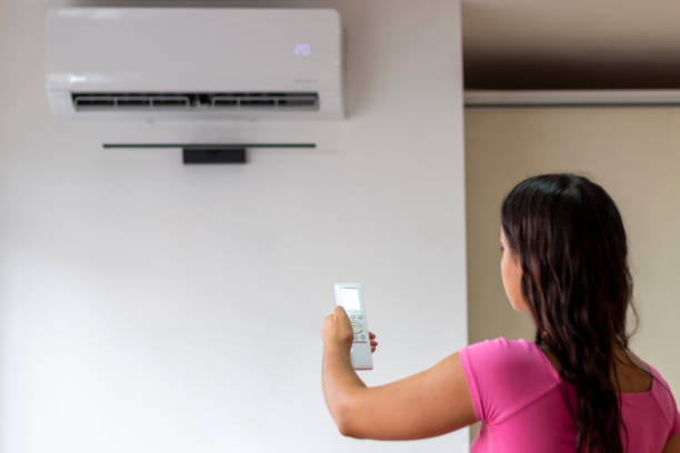 istock Young woman adjusting modern AC system, regulating temperature and enjoying cool fresh air at home 2192143869