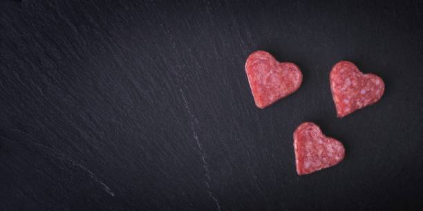 istock Salami in heart shape sliced on a cutting board, seen directly above. Panoramic image with copy space. 2192145794