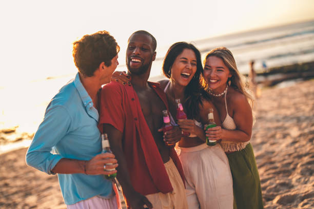 istock Group of friends laughing and enjoying drinks on a sunny beach 2192148816