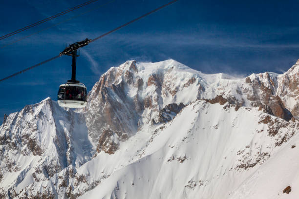 Courmayeur, Italy - 15 March 2023: Ski lift carrying skiers to the top of the mountain in the Courmayeur resort, View of Mount Blanc