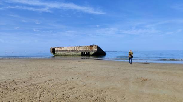 A young boy exploring the Normandy landing beach during D-Day.