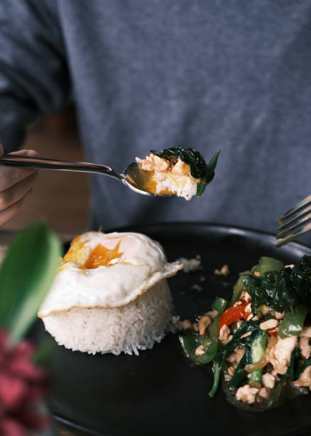 istock Thai Stir-Fried Chicken with Hot Basil Served with Jasmine Rice and a Perfectly Fried Egg, Presented on a Black Plate in a Rustic Setting 2192161600