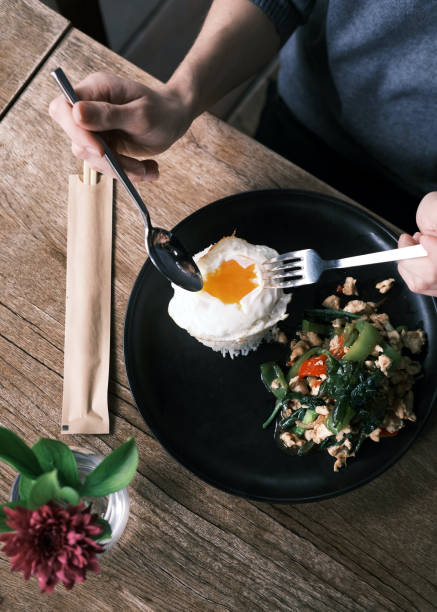 istock Thai Stir-Fried Chicken with Hot Basil Served with Jasmine Rice and a Perfectly Fried Egg, Presented on a Black Plate in a Rustic Setting 2192161608