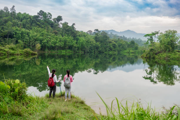 Two friends hikers outdoors at a beautiful lake destination with their hiking poles and backpacks enjoying the breathtaking scenes