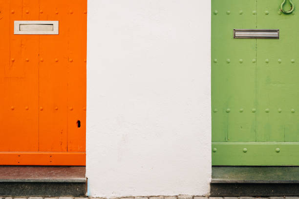 Minimalist composition featuring vibrant orange and green doors separated by a white wall, highlighting contrasting colors and symmetry.