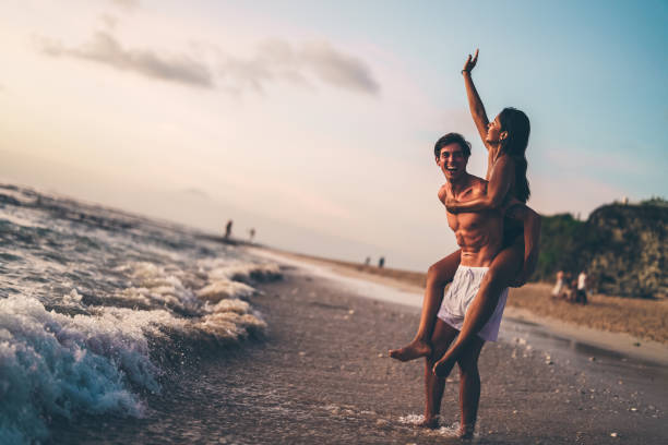 istock Playful couple enjoying a fun time on the beach during sunset 2192165346