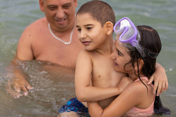 Father and children share a heartwarming moment as they swim and have fun in the sea.