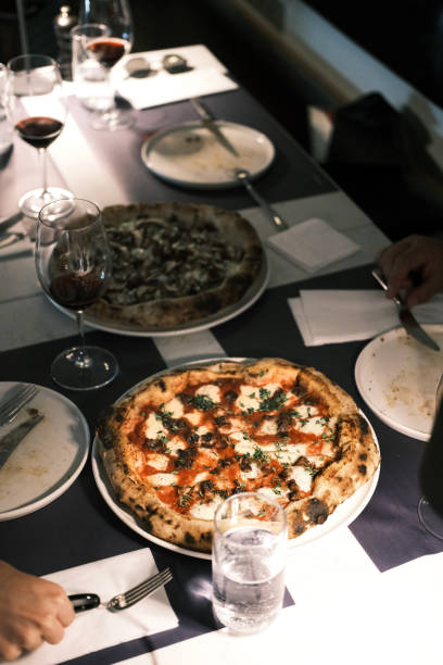 istock Authentic Italian dining experience with gourmet Neapolitan pizza, wood-fired pizza with fresh mozzarella, tomato sauce, and herbs, served with red wine in an elegant restaurant setting, fine dining atmosphere, cozy and stylish dinner 2192168893