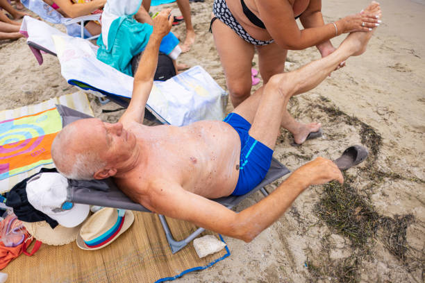 Close up view of sandy male feet resting on beach lounger with blurred in turquoise Atlantic sea. Miami Beach. USA.