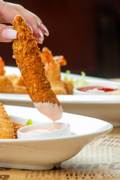 Crispy fried shrimp skewer with green sauce on dark plate. Delicious seafood appetizer or snack for menu.