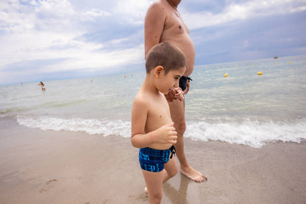 istock Father and Son with Disability Strolling on the Beach 2192171227