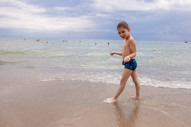 A child with mental disability walks confidently along the beach, with the sea stretching out before him.