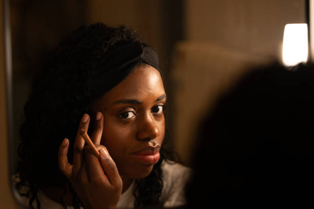 istock Young woman applying makeup with precision in front of a mirror, surrounded by warm lighting in a cozy room, enhancing her natural beauty and embracing self-care 2192171476