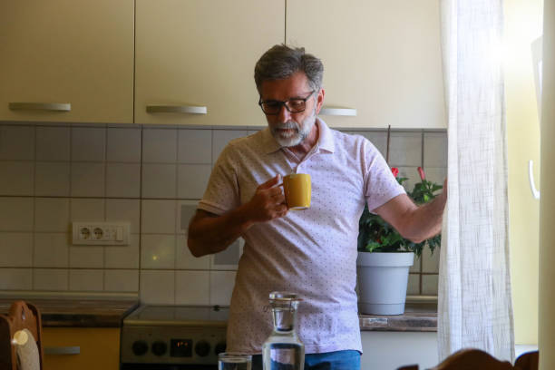 istock Senior casual man drinking in his kitchen and looking outside 2192174031
