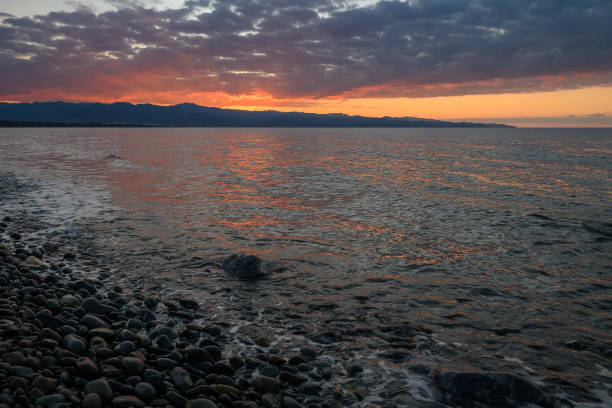 istock Vibrant sunset reflecting over calm waters along a rocky shoreline in a tranquil coastal setting 2192178771