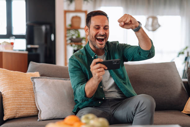 istock Excited man winning at a mobile game on the sofa at home 2192181384