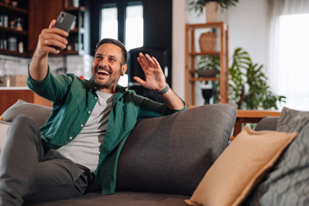 istock Happy man making a video call with mobile phone waving to the screen 2192181386