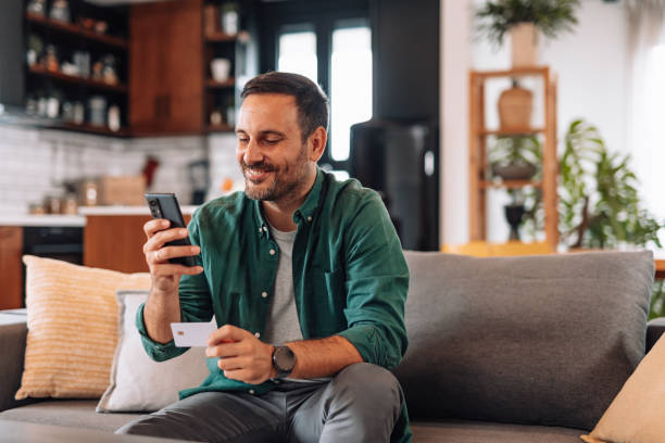 istock Man shopping online using smartphone and credit card at home 2192181409