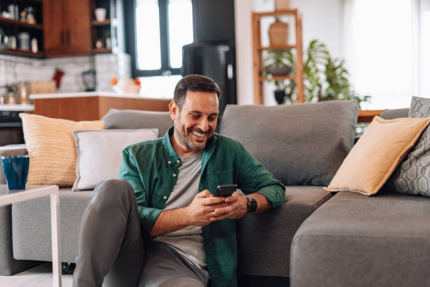 istock Mid adult man using mobile phone and smiling at home 2192181417