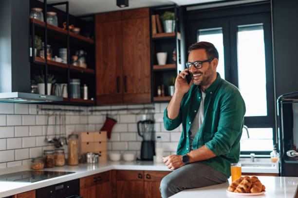 istock Man talking on the phone and smiling while having breakfast in the kitchen 2192181468
