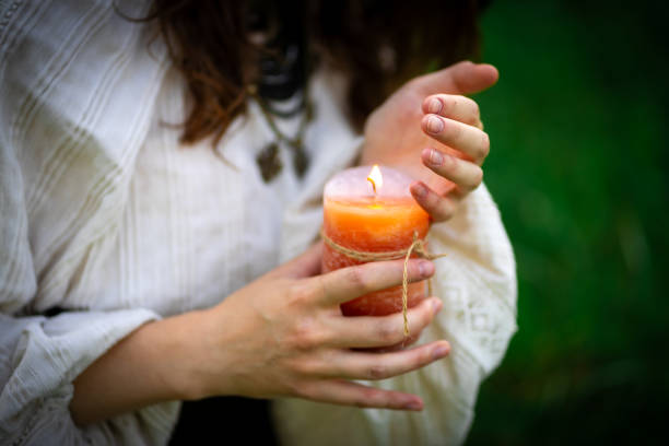 Female hands in national costume hold a burning candle.