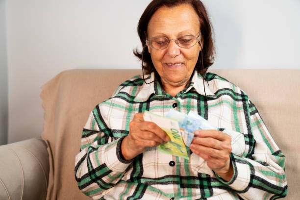 istock Close-up of elderly woman's hands holding a stack of euro banknotes 2192183246