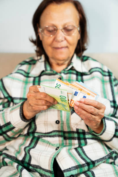 istock Close-up of elderly woman's hands holding a stack of euro banknotes 2192183314