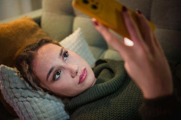 istock Young woman relaxing on sofa using smartphone at night 2192184101
