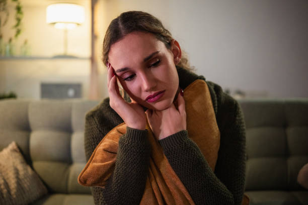 istock Sad young woman sitting on sofa holding a pillow at home 2192184130