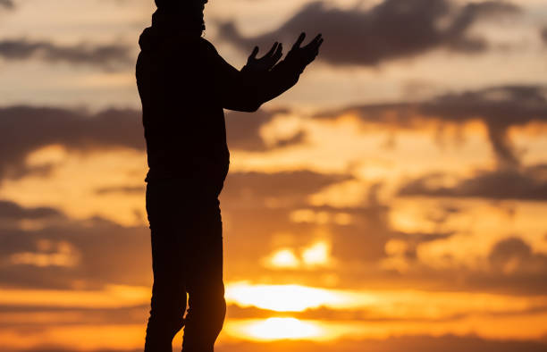 Silhouette of prayer having worship and praying with hands open at sunset Silhouette of muslim woman prayer having worship and praying with hands open doing dua to Allah at sunset . High quality photo i love allah in arabic silhouettes stock pictures, royalty-free photos & images