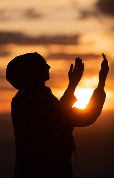 Silhouette of Muslim woman prayer having worship and praying with hands open doing dua to Allah at sunset. Silhouette of muslim woman prayer having worship and praying with hands open doing dua to Allah at sunset . High quality photo i love allah in arabic silhouettes stock pictures, royalty-free photos & images
