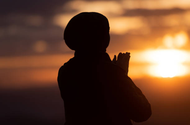 Silhouette of Muslim woman prayer having worship and praying with hands for thank god Allah at sunset. Silhouette of muslim woman prayer having worship and praying with hands open doing dua to Allah at sunset . High quality photo i love allah in arabic silhouettes stock pictures, royalty-free photos & images