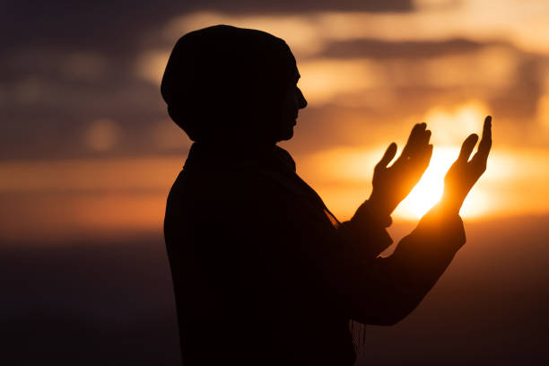 Silhouette of Muslim woman prayer having worship and praying with hands open doing dua to Allah at sunset. Silhouette of muslim woman prayer having worship and praying with hands open doing dua to Allah at sunset . High quality photo i love allah in arabic silhouettes stock pictures, royalty-free photos & images