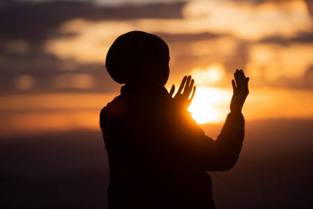 Silhouette of muslim woman prayer having worship and praying with hands open doing dua to Allah at sunset Silhouette of muslim woman prayer having worship and praying with hands open doing dua to Allah at sunset . High quality photo i love allah in arabic silhouettes stock pictures, royalty-free photos & images